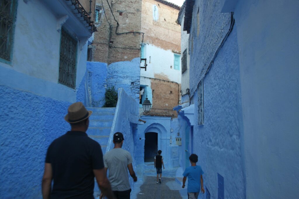 A group of people walking through the iconic blue alleys of Chefchaouen, Morocco.