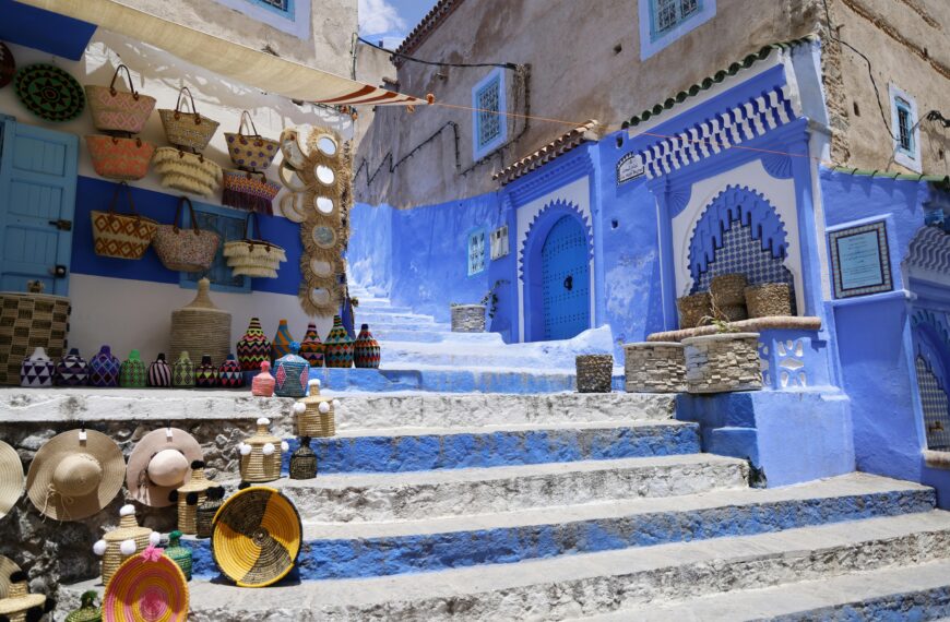 Colorful market scene with traditional Moroccan architecture and merchandise on display in a sunlit alley.