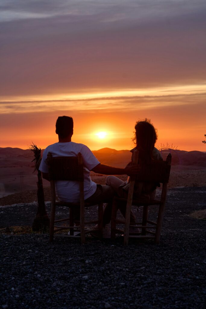 A silhouetted couple enjoys a breathtaking sunset view over Marruecos desert landscape.